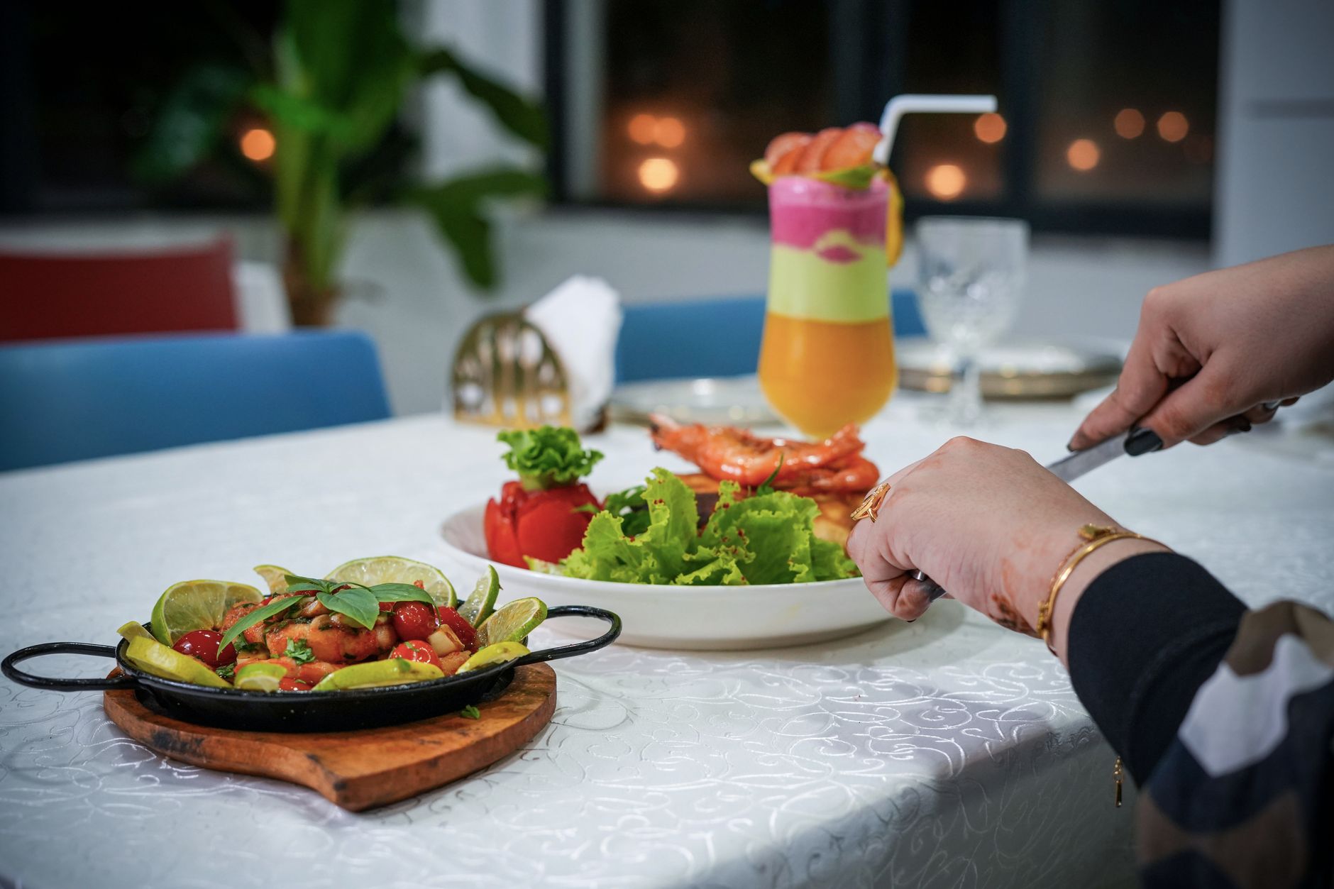 An elegant dining table setup with a colorful cocktail, fresh salad, and plated dish ready to serve. — Introducing Thai Food
