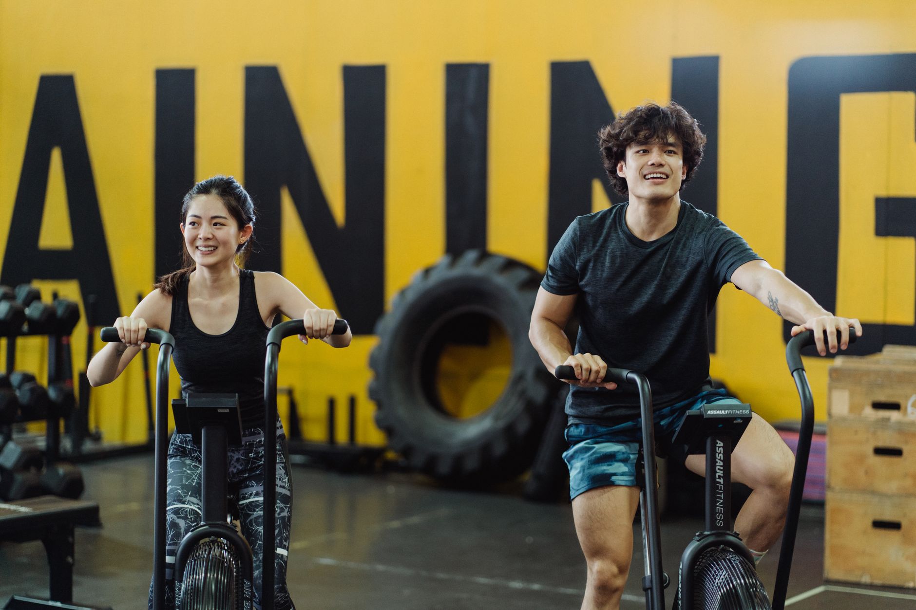 A man and woman enjoying a workout on indoor cycles at a gym, expressing fitness and joy. — Weight Reduction: 4 Reasons You a